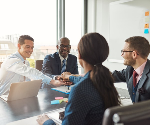 Successful diverse team placing hands one above another